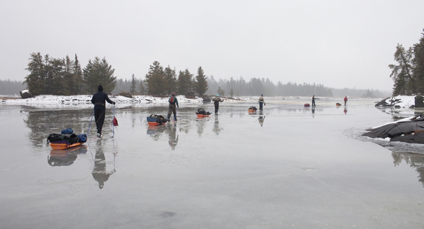 一行人拉一条线的小雪橇在结冰的湖