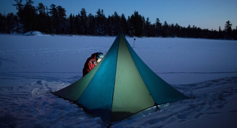 一个帐篷躺在一个下雪的景观被一个人的头灯